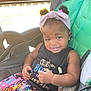 child, toddler, stroller, headband, pigtails, smile, colorful_clothing, black_tank_top, earrings, railroad_tracks, outdoor, daylight, baby, cute, happy, portrait, sitting, infant, fashion, seat