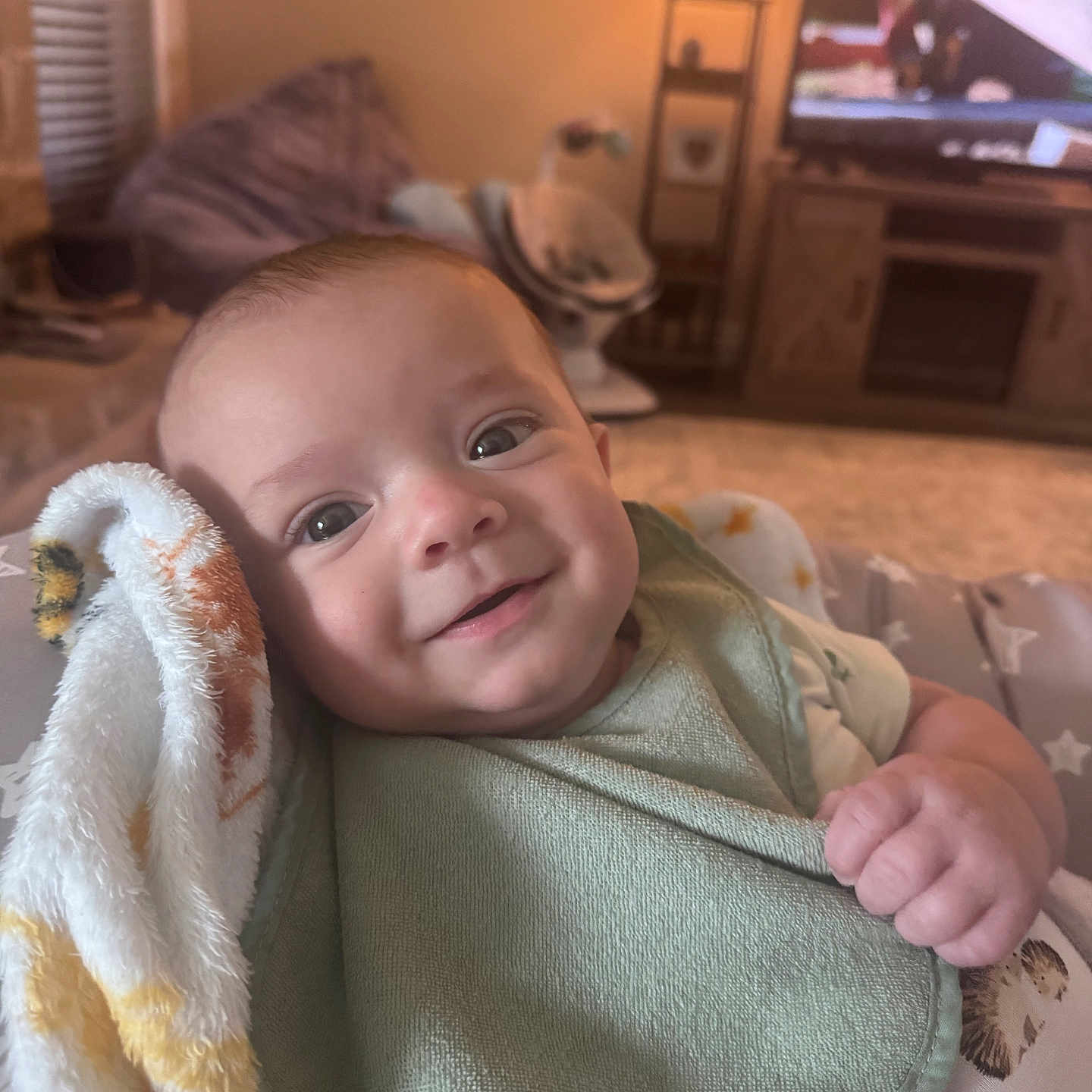 Abbott joined the competition — help win amazing prizes! baby, smiling, blanket, bib, indoor, living_room, lamp, television, furniture, cozy, infant, child, happy, person, portrait, cute, warm_lighting, soft_texture, relaxing, home