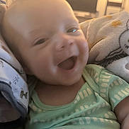 Abbott joined the competition — help win amazing prizes! baby, smiling, infant, green_clothing, blanket, cozy, happy, face, indoors, soft_lighting, cute, child, portrait, newborn, sleepwear, expression, closeup, comfort, resting, warm