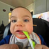 Camron is registered to the contest to win money with this photo: baby, child, face, spoon, bib, blue_eyes, close_up, indoor, high_chair, feeding, person, furniture, television, living_room, hand, clothing, home, cute, expression, infant