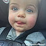 baby, child, car_seat, blue_eyes, tongue_out, seatbelt, safety, close_up, infant, cute, face, person, casual_clothing, indoor, car_interior, warning_sticker, expression, portrait, young_child, seat_harness