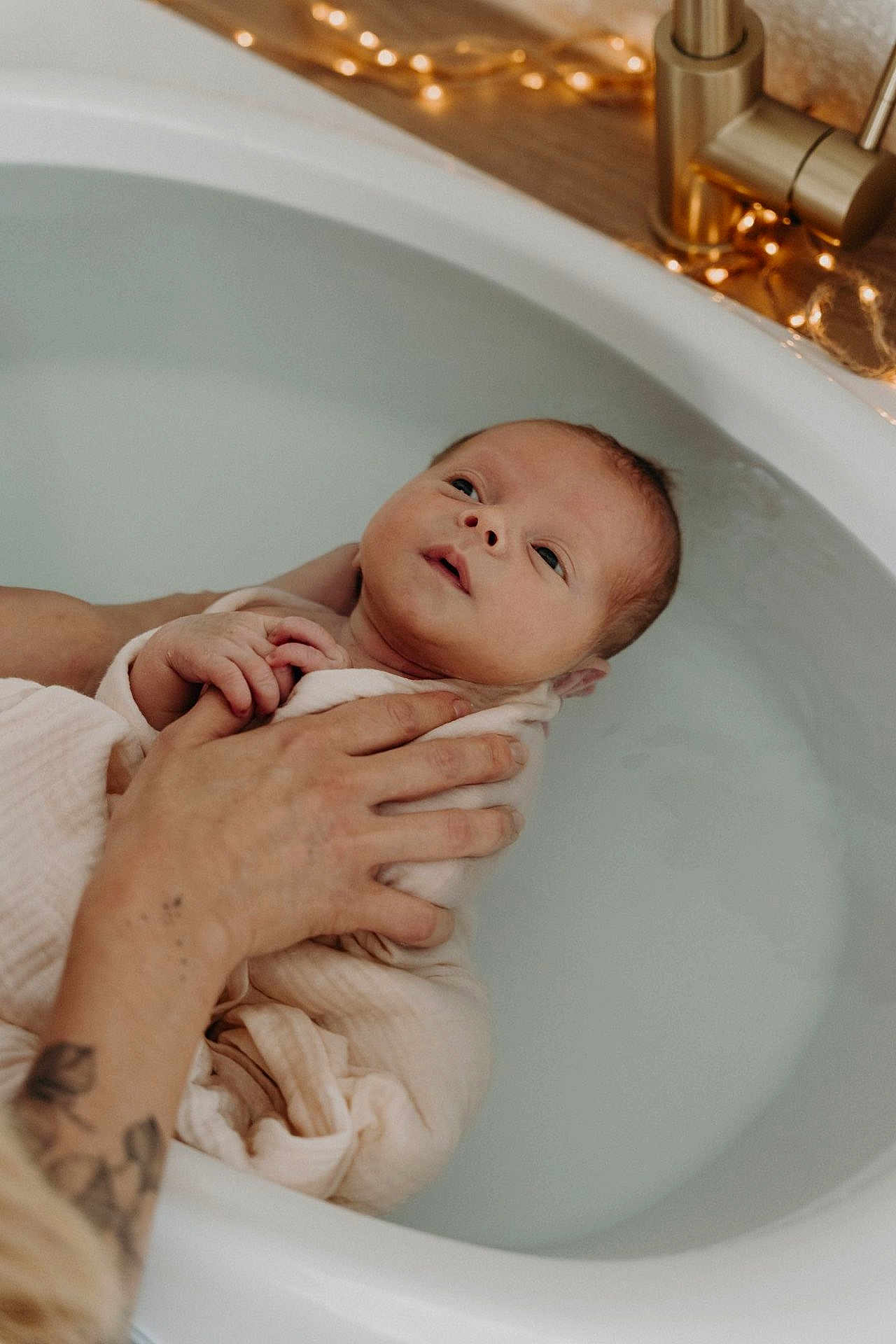 Arthur participe au concours pour gagner de l'argent avec cette photo : newborn, baby, bathtub, water, blanket, hand, tattoo, infant, bath, skin, relaxation, soothing, wrapped, adult_hand, fairy_lights, warmth, care, gentle, peaceful, indoors
