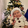 baby, child, christmas_tree, holiday, festive, santa_hat, snowman_outfit, decorations, ornaments, tinsel, indoor, person, cute, face, celebration, seasonal, festivity, holding, christmas, winter
