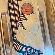 Zarih is registered to the contest to win money with this photo: newborn, baby, hospital, bassinet, blanket, striped_blanket, swaddled, infant, sleeping, cap, bed, medical, wrapped, cute, child, person, healthcare, nursery, soft, peaceful
