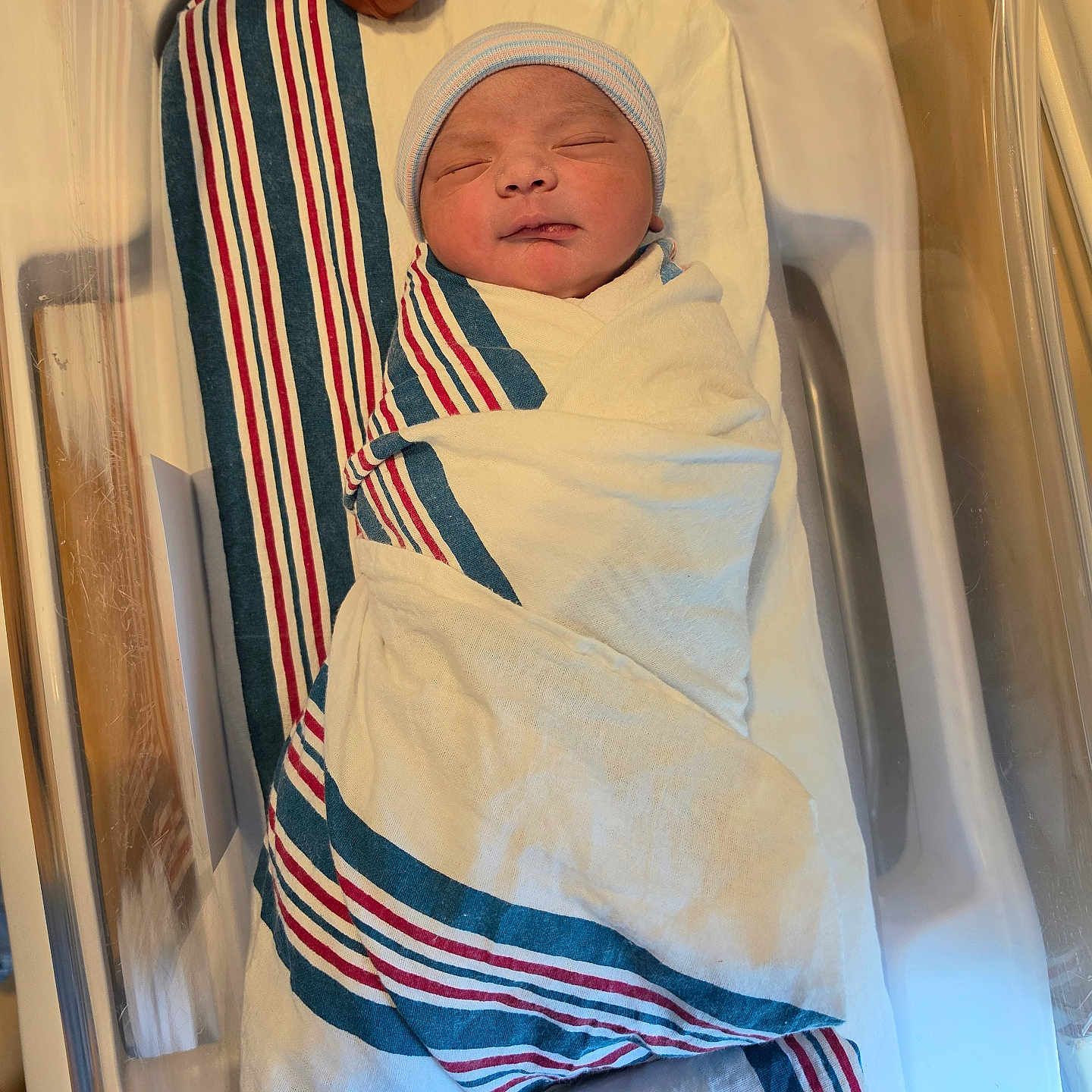 Zarih is registered to the contest to win money with this photo: newborn, baby, hospital, bassinet, blanket, striped_blanket, swaddled, infant, sleeping, cap, bed, medical, wrapped, cute, child, person, healthcare, nursery, soft, peaceful