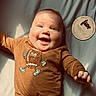 Oliver joined the competition — help win amazing prizes! baby, infant, smiling, face, onesie, football, milestone_card, five_months, child, cute, happy, lying_down, soft_surface, sunlight, portrait, clothing, hand, head, closeup, expression