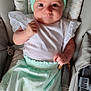 baby, infant, headband, car_seat, clothing, white_shirt, mint_green_pants, socks, face, eyes, hand, seatbelt, baby_toys, indoor, portrait, cute, child, young_baby, soft_lighting, closeup