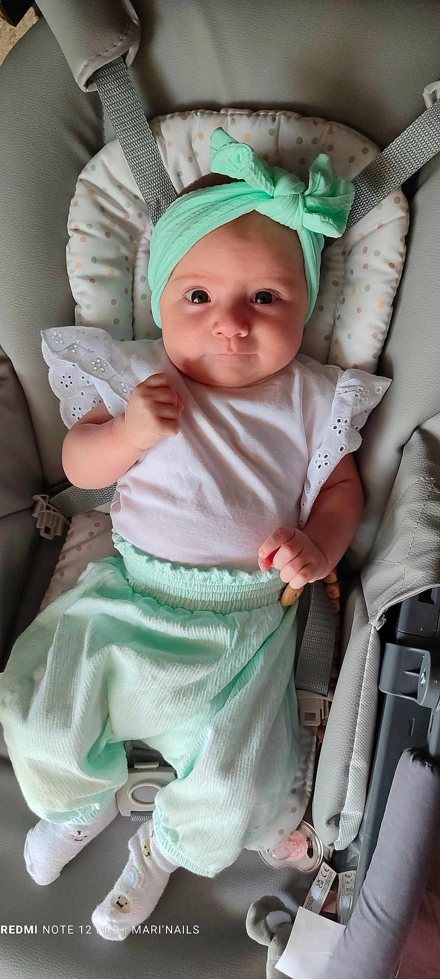 Lyorah participe au concours pour gagner de l'argent avec cette photo : baby, infant, headband, car_seat, clothing, white_shirt, mint_green_pants, socks, face, eyes, hand, seatbelt, baby_toys, indoor, portrait, cute, child, young_baby, soft_lighting, closeup