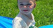 Monty joined the competition — help win amazing prizes! blue_mat, casual_clothing, child, daytime, face, garden, grass, green_shorts, happy, nature, outdoor, playing, portrait, sitting, smiling, summer, sunlight, toddler, white_tshirt, young_child