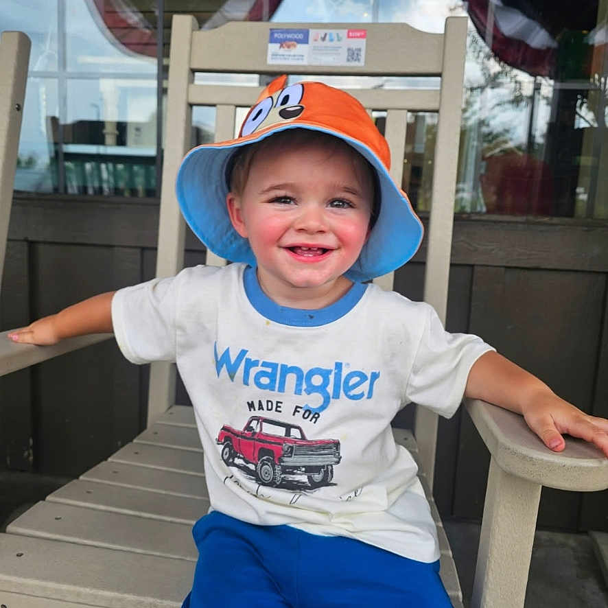 Monty joined the competition — help win amazing prizes! blue_pants, bucket_hat, casual_clothing, chair, child, cute, daylight, happy, hat, outdoor, person, portrait, reflection, sitting, smiling, tshirt, window, wooden_chair, wrangler, young_child