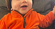 Jaxon joined the competition — help win amazing prizes! baby, cap, clothing, coat, couch, face, furniture, happy, hat, head, hood, hoodie, jacket, knitwear, pants, person, photography, portrait, smile, sweater
