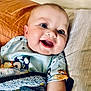 baby, bed, blanket, blue, child, clothing, comfort, cozy, cute, expression, face, happy, indoors, infant, lying_down, pillow, portrait, skin, smiling, young