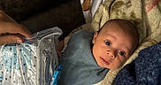 Rj is registered to the contest to win money with this photo: baby, infant, blanket, hand, candy, face, person, cozy, patterned_cloth, animal_print, wrapped, curious, wide_eyes, indoor, soft_texture, protective_hand, packaged_item, laying_down, close_up, young_child