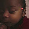 Rj is registered to the contest to win money with this photo: baby, sleeping, face, infant, closeup, red_clothing, peaceful, skin, head, hand, portrait, young_child, indoors, resting, cute, newborn, calm, soft_light, emotion, heart_emoji