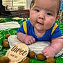 baby, infant, three_months, blue_shirt, yellow_stripes, pillow, mini_football, green_mat, indoors, curious_expression, drool, face, hands, child, cute, playtime, closeup, portrait, newborn, smiling