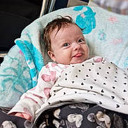 Lilith joined the competition — help win amazing prizes! baby, infant, blanket, cozy, cute, tongue_out, smile, face, clothing, pattern, soft, indoors, child, wrapped, head, hair, playful, happy, person, resting