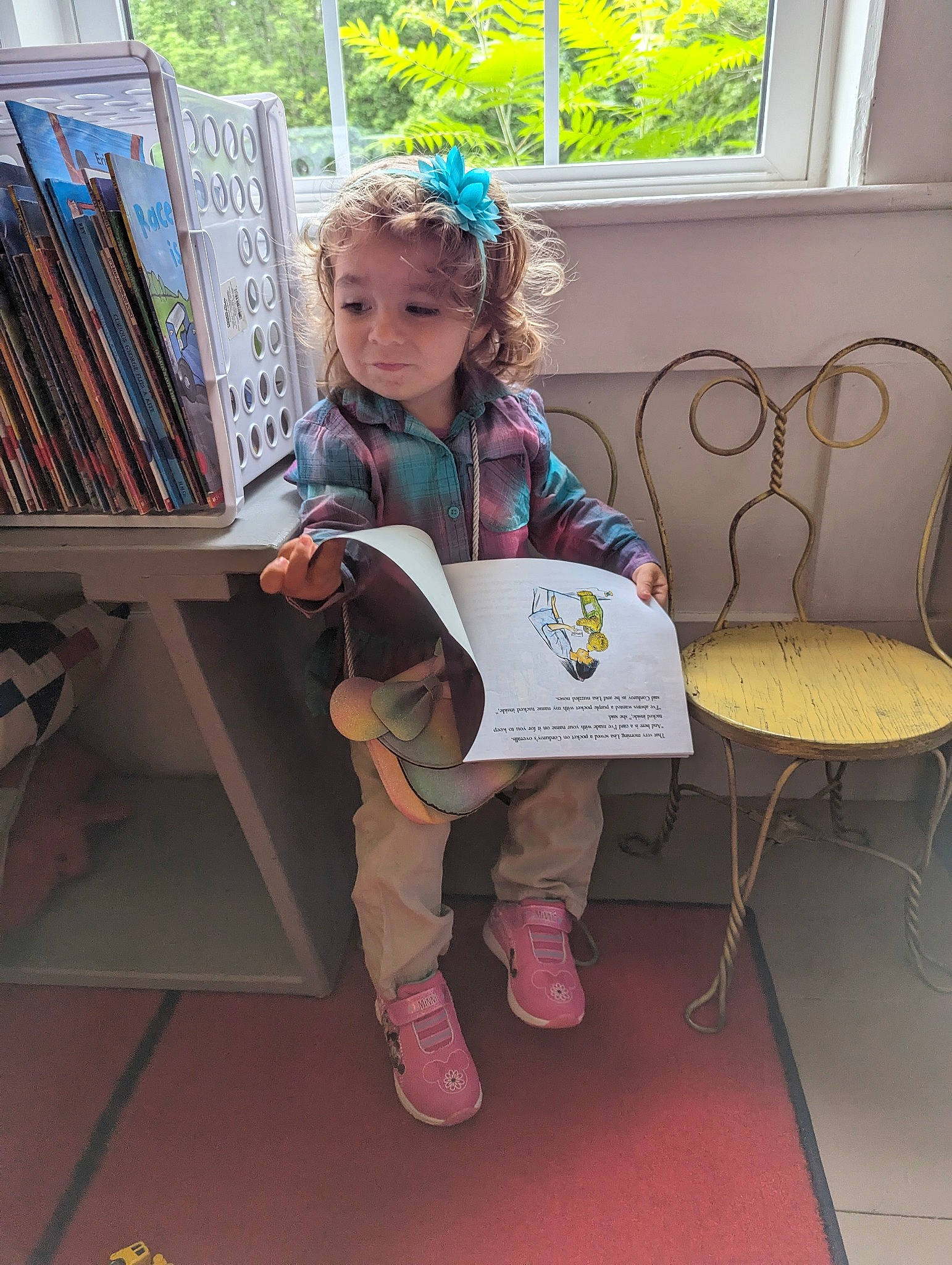 Kinzie is registered to the contest to win money with this photo: art, book, bookcase, chair, child, event, fun, furniture, learning, leisure, pattern, person, publication, reading, room, shelf, shelving, sitting, toddler, visual_arts