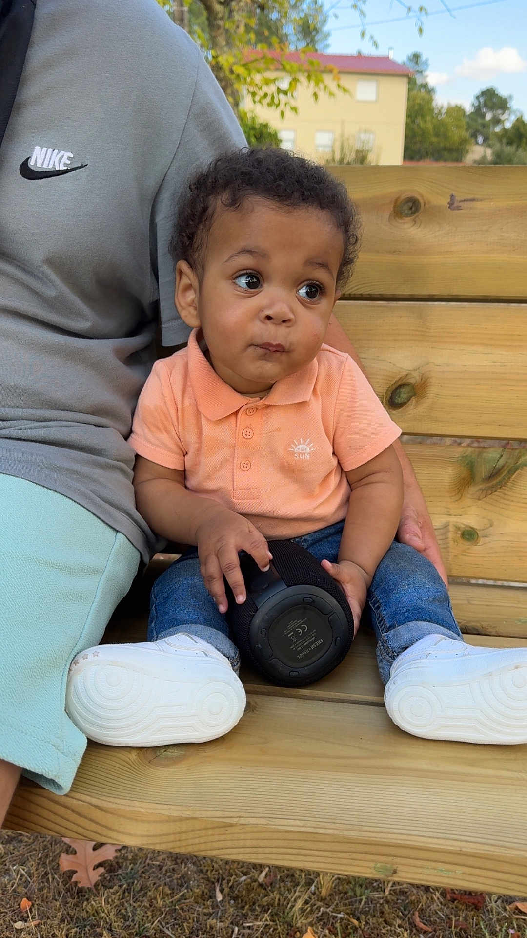 Lyam a rejoint le concours — aidez-le/la à gagner de superbes lots ! toddler, child, bench, outdoor, person, jeans, sneakers, curly_hair, speaker, clothing, wood, nature, grass, daylight, casual, expression, sitting, holding, adult, nike