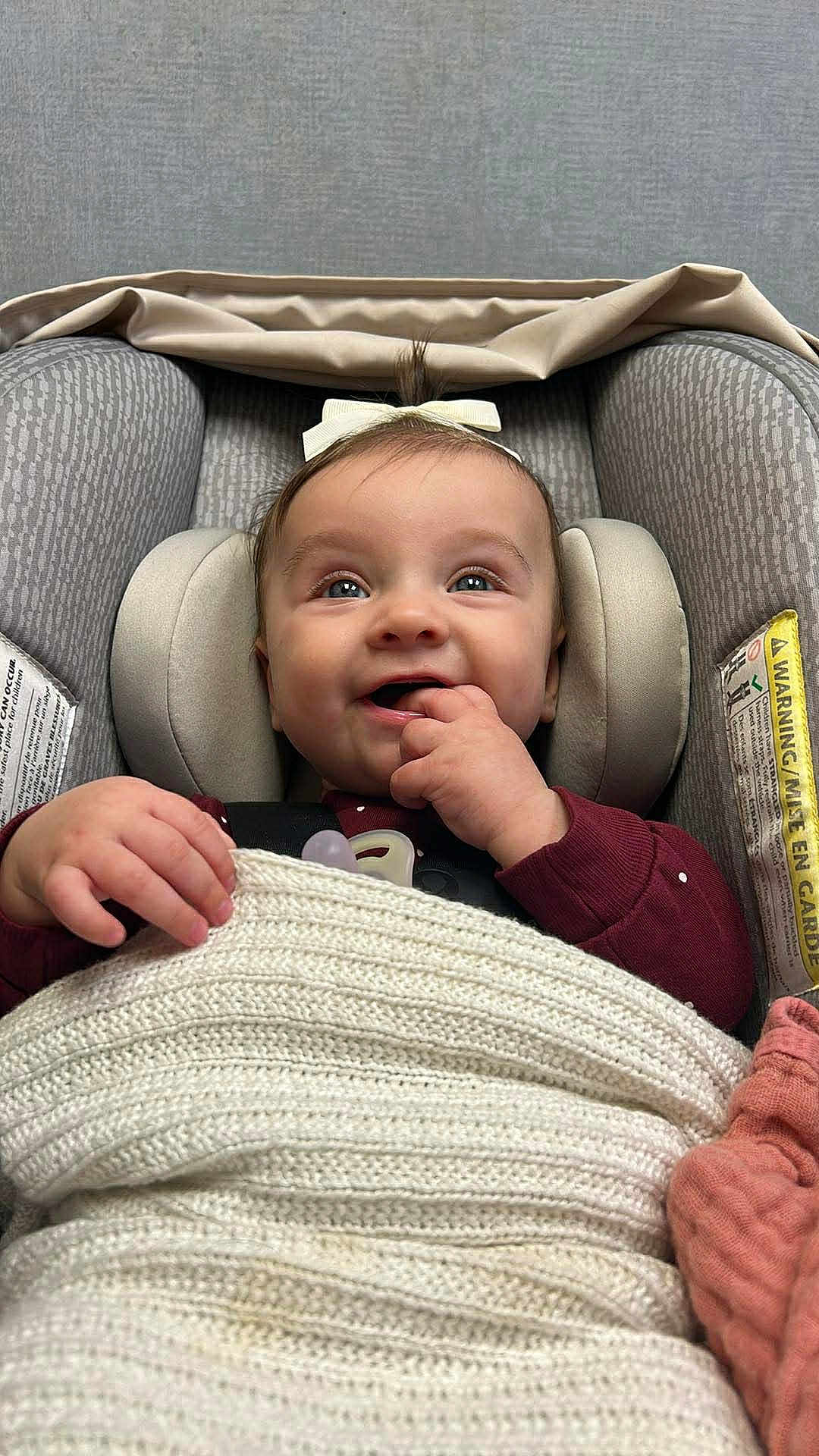 Savannah is registered to the contest to win money with this photo: baby, infant, car_seat, blanket, bow, smiling, happy, child, face, hand, cozy, knit, comfort, seatbelt, indoors, cute, portrait, head_support, clothing, pacifier