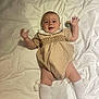 baby, infant, smiling, lying_down, white_sheet, beige_outfit, knitted_socks, pacifier, happy, cute, small_hands, crawling_age, indoors, soft_lighting, child, portrait, human, adorable, playful, resting