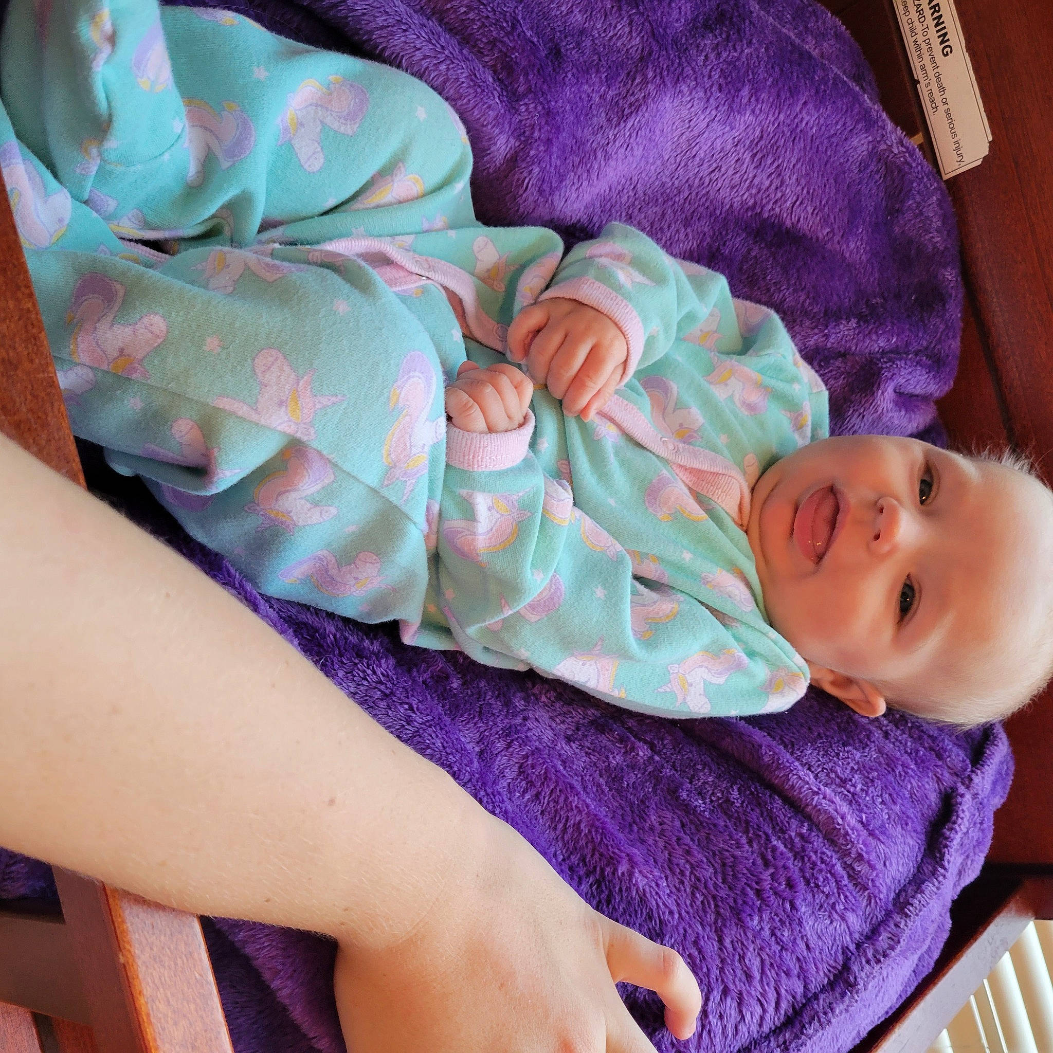 Amelia is registered to the contest to win money with this photo: arm, baby, baby_toddler_clothing, cheek, child, comfort, eye, finger, hand, human_body, leg, linens, person, pink, purple, skin, sleeve, smile, textile, toddler