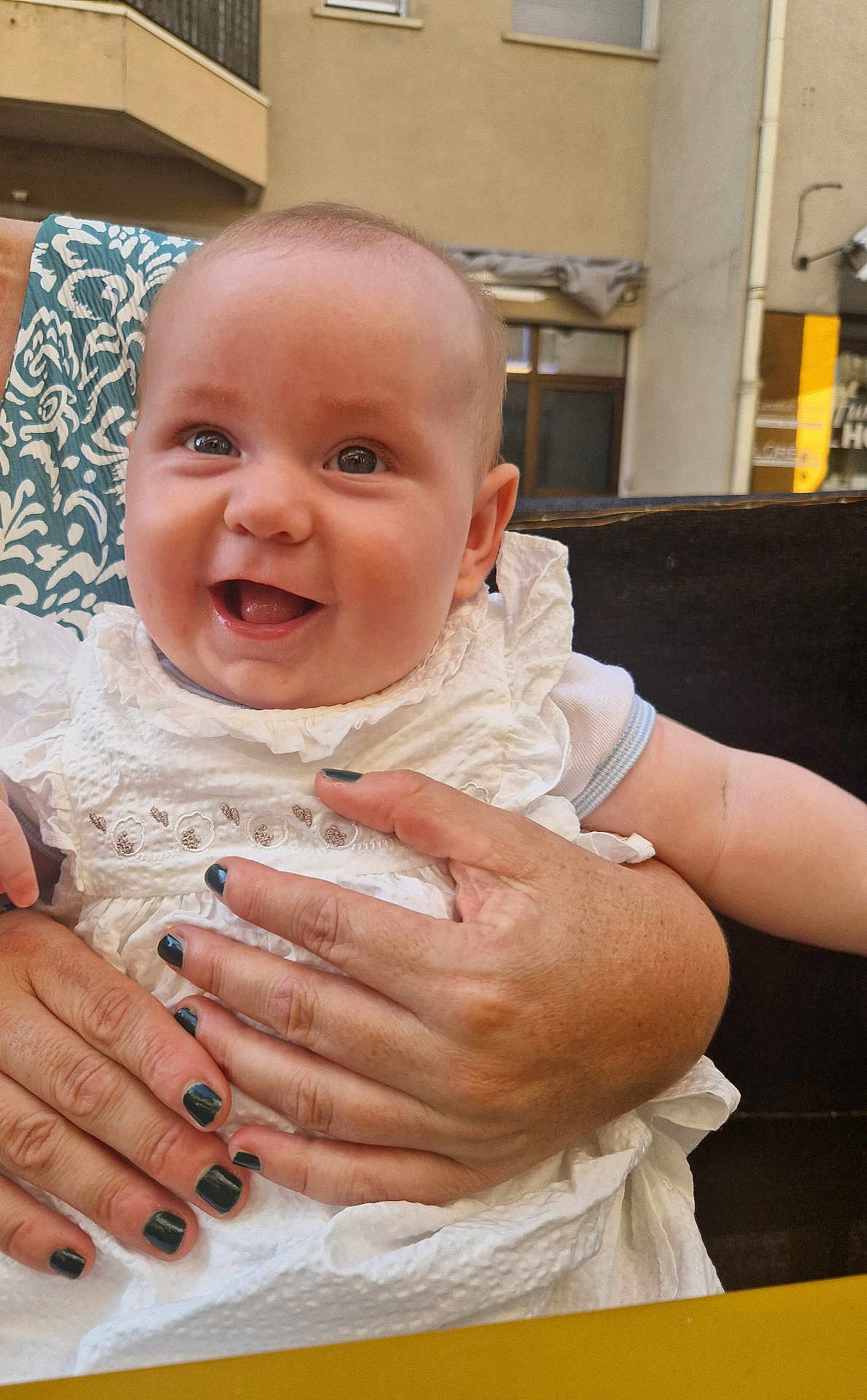 Myla a rejoint le concours — aidez-le/la à gagner de superbes lots ! baby, child, smiling, happy, person, hand, nail_polish, white_dress, clothing, face, portrait, infant, outdoor, building, window, skin, holding, cute, young, people