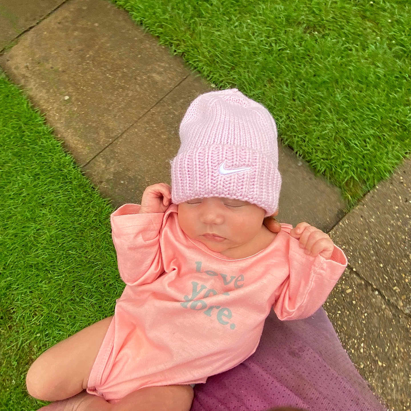 Iraheta is registered to the contest to win money with this photo: baby, child, closeup, cute, grass, hands, infant, knit_hat, nature, newborn, outdoor, pathway, peaceful, person_holding, pink_hat, pink_onesie, resting, sleeping, soft_lighting, toddler