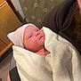 Elliana is registered to the contest to win money with this photo: newborn, baby, blanket, hat, striped_hat, beard, arm, chair, furniture, person, indoors, wrapped, resting, portrait, human, infant, soft, cozy, seated, closeup