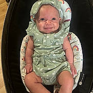 Elliana joined the competition — help win amazing prizes! baby, infant, smile, green_outfit, headband, baby_seat, rainbow_pattern, cute, happy, child, indoor, portrait, clothing, legs, arms, face, person, seat, comfort, expression