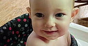 Juniper joined the competition — help win amazing prizes! baby, child, infant, smiling, portrait, high_chair, indoor, kitchen, home, seated, face, eyes, bald, arm, hand, patterned_clothing, furniture, wood_floor, toy, cozy