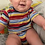 baby, child, smiling, striped_clothing, onesie, sitting, bed, happy, cute, indoor, face, cheeks, arms, legs, person, infant, skin, head, eyes, expression