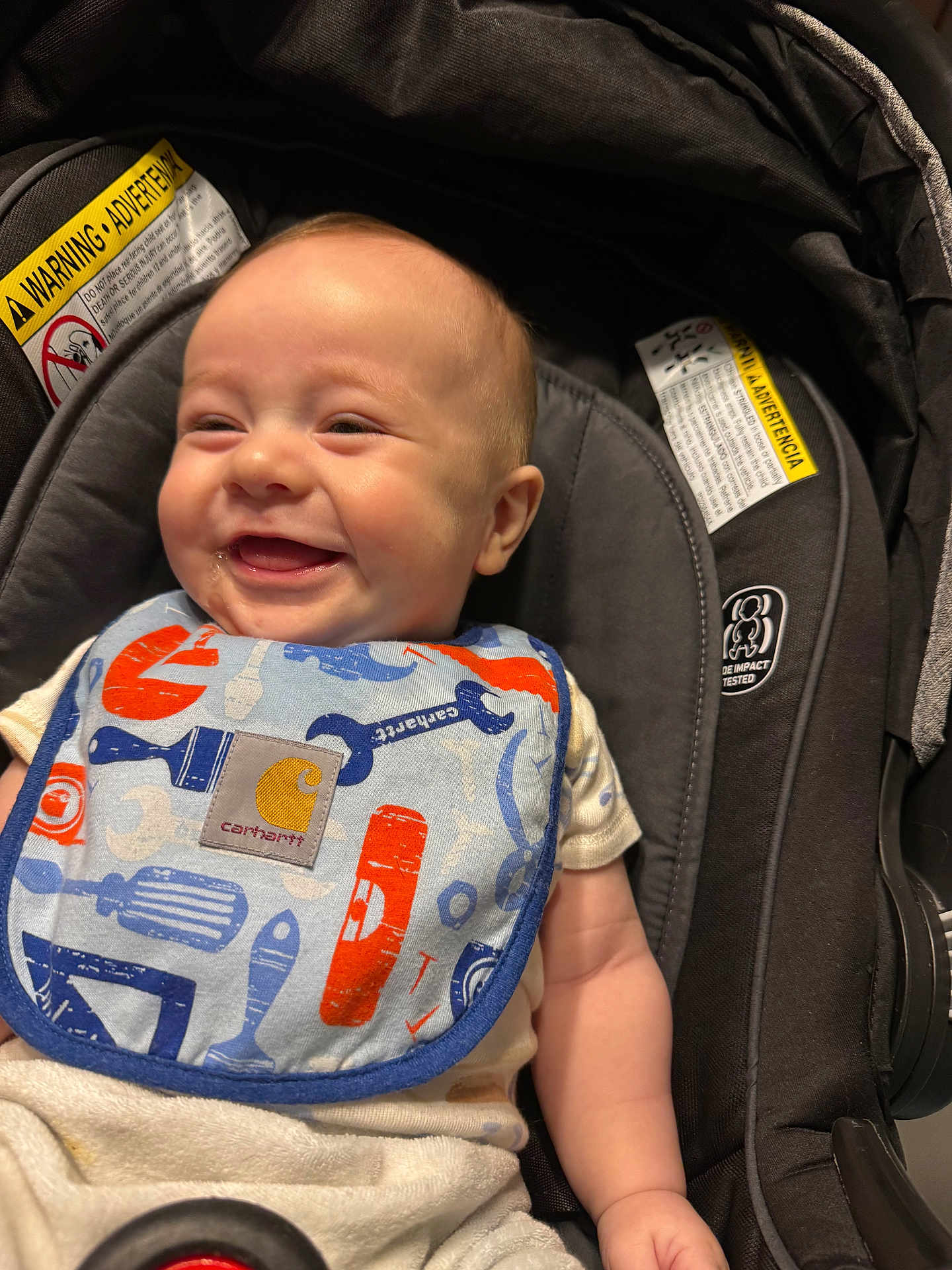 Manuelito is registered to the contest to win money with this photo: baby, smiling, car_seat, bib, happy, infant, child, clothing, seat, portrait, closeup, cute, person, indoor, baby_bib, sitting, joyful, young_child, infancy, expression