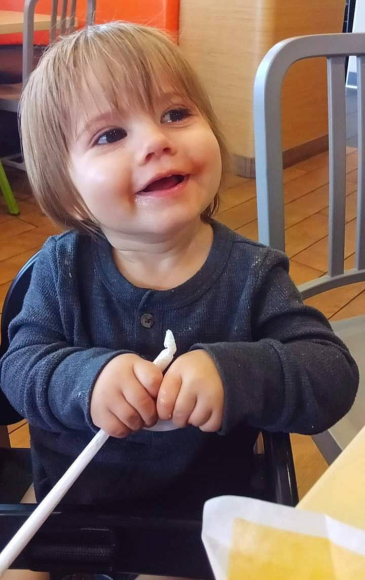 Ashton is registered to the contest to win money with this photo: baby, baby_toddler_clothing, bangs, chair, cheek, child, chin, comfort_food, finger, gesture, happy, joy, person, sitting, skin, sleeve, smile, t_shirt, tableware, thumb