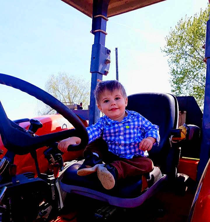 Ashton is registered to the contest to win money with this photo: amusement_ride, auto_part, automotive_exterior, automotive_tire, automotive_wheel_system, fun, joy, leisure, motor_vehicle, nonbuilding_structure, person, playground, recreation, riding_toy, sitting, sky, steering_wheel, toddler, tree, vehicle