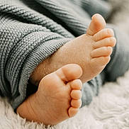 Julian is registered to the contest to win money with this photo: baby_feet, toes, knitted_pants, gray_clothing, close_up, soft_texture, fluffy_surface, infant, cute, cozy, skin, foot, sleepwear, baby, newborn, warm_lighting, relaxation, comfort, small, resting