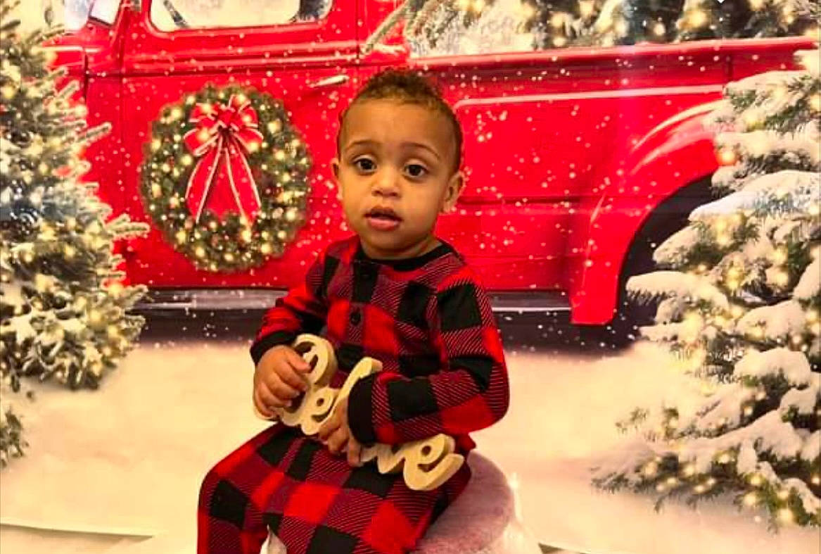 Maveryk is registered to the contest to win money with this photo: christmas, christmas_decoration, christmas_eve, christmas_ornament, christmas_tree, event, facial_expression, fun, happy, holiday, mammal, ornament, person, plant, red, standing, tartan, toddler, tree, white