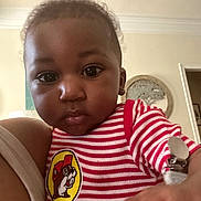 Kaji is registered to the contest to win money with this photo: baby, child, face, indoor, striped_shirt, cartoon_patch, curious, person, young_child, hand, expression, clothing, portrait, skin, hair, room, furniture, light, casual, closeup