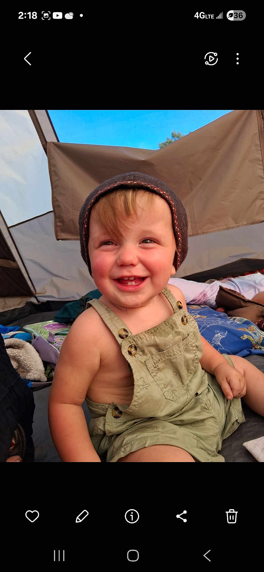 Derek is registered to the contest to win money with this photo: toddler, child, smiling, hat, overalls, tent, camping, outdoor, happy, baby, clothing, portrait, person, fabric, blanket, playful, cute, nature, daylight, seated