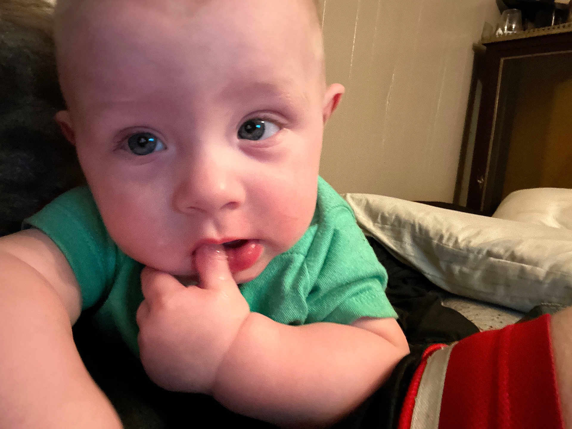 Malachi joined the competition — help win amazing prizes! baby, infant, child, closeup, face, finger, hand, blue_eyes, green_shirt, bed, pillow, furniture, indoor, curious, chubby_cheeks, skin, person, portrait, cute, lying_down