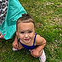 child, toddler, grass, outdoor, blue_clothing, pink_shoes, scooter, curious, playful, person, young_child, summer, greenery, squatting, casual, daylight, nature, lawn, fun, cute