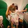 Loujayne participe au concours pour gagner de l'argent avec cette photo : airplane, barefoot, candid, child, clothing, dress, foot, green_seat, holding, interior, knee, person, playful, seat, seatback, standing, toddler, travel, window, young_child