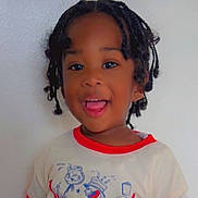 Zyon is registered to the contest to win money with this photo: child, smiling, portrait, indoor, white_wall, braided_hair, t_shirt, red_trim, toddler, happy, teeth, brown_eyes, dark_skin, casual_clothing, close_up, head_and_shoulders, playful, standing, person, expression