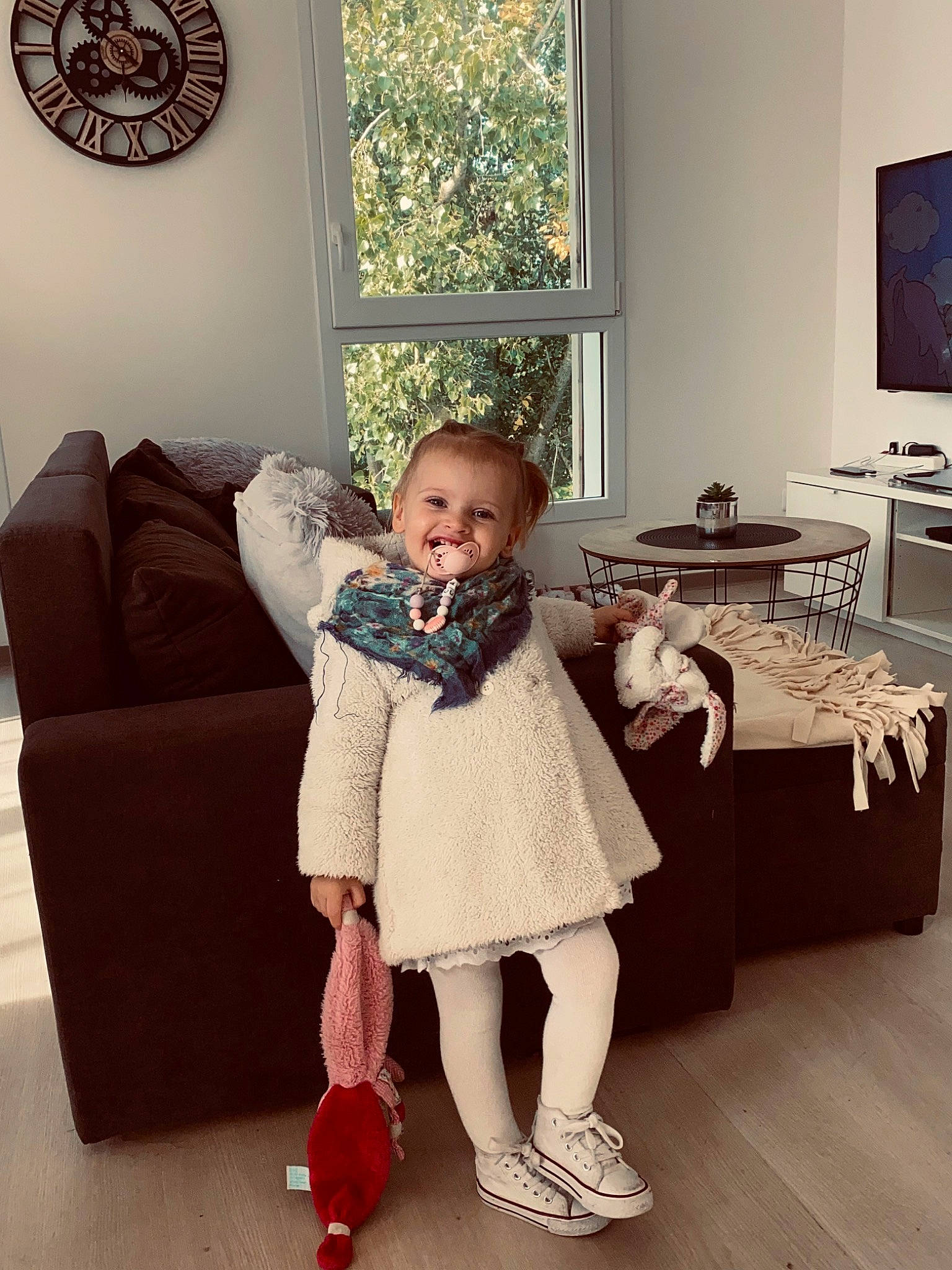 Camilia participe au concours pour gagner de l'argent avec cette photo : baby_toddler_clothing, child, comfort, couch, dress, event, floor, flooring, happy, hardwood, human_leg, interior_design, joy, living_room, person, picture_frame, shoe, sitting, table, toddler