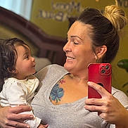 Amari joined the competition — help win amazing prizes! child, toddler, mother, parent, family, portrait, selfie, mirror, smiling, happy, indoors, home, baby, infant, white_clothing, gray_shirt, red_phone, tattoo, hair_bun, hearts