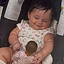 baby, child, doll, car_seat, smile, floral_onesie, infant, cute, chubby, hand, toy, seated, indoor, person, young_child, cute_expression, content, skin, hair, play