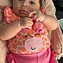 baby, infant, headband, pink_clothing, orange_clothing, giraffe_pattern, cute, portrait, face, hands, lying_down, cushion, soft_texture, indoors, child, closeup, apparel, adorable, young_child, person