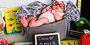 Julianna is registered to the contest to win money with this photo: baby, basket, glasses, headband, bow, blanket, books, chalkboard, class_of_2043, dr_seuss, reading, child, cute, cozy, feet, hand, indoor, table, decor, person
