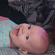 Loralie is registered to the contest to win money with this photo: baby, smiling, face, head, child, infant, lying_down, clothing, fabric, blanket, bed, pattern, soft, happy, cute, skin, eyes, mouth, indoors, portrait
