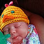 baby, sleeping, hat, knitted_hat, yellow, chick_hat, pacifier, floral_outfit, colorful, infant, person, arm, closeup, cute, peaceful, resting, indoors, soft_light, portrait, child