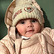 Joy a rejoint le concours — aidez-le/la à gagner de superbes lots ! baby, child, face, hat, knitted_hat, puffer_jacket, pink_clothing, cute, infant, person, portrait, wide_eyes, winter_clothing, warm, apparel, smile, indoor, close_up, headwear, fashion